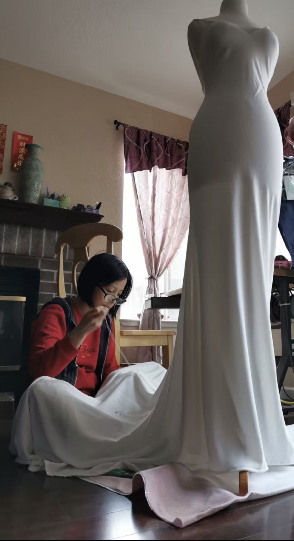 The seamstress hand-finishing a gown on the dress form